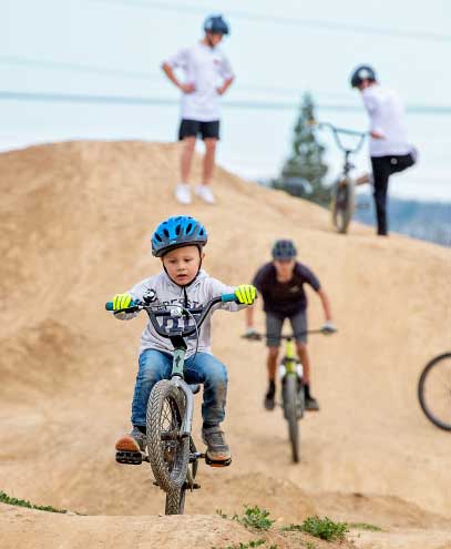 child jumping a dirt ramp on a dirt bike.