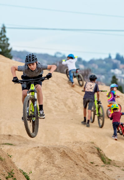 young boy jumping off dirt ramp and BMX park