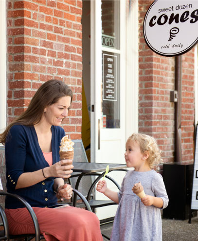 mother and daughter enjoying ice cream cones while sitting outdoors