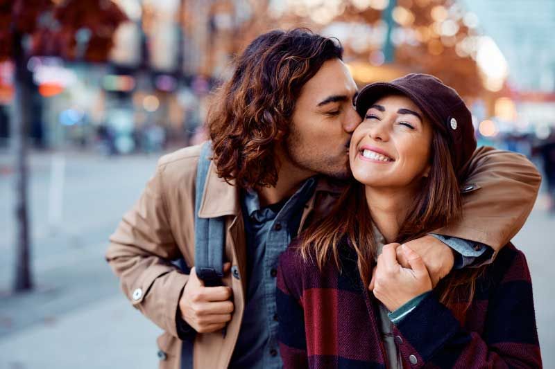 man kissing woman on the cheek while she smiles