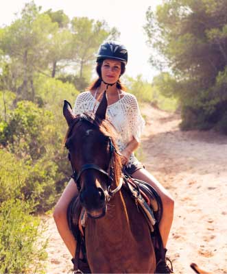 Female horseback riding on dirt trail