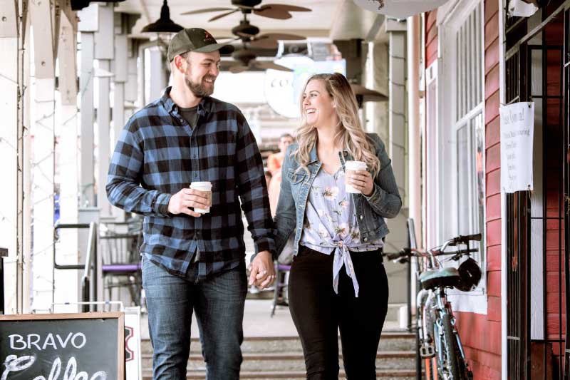 A couple holding hands while walking by coffee shop