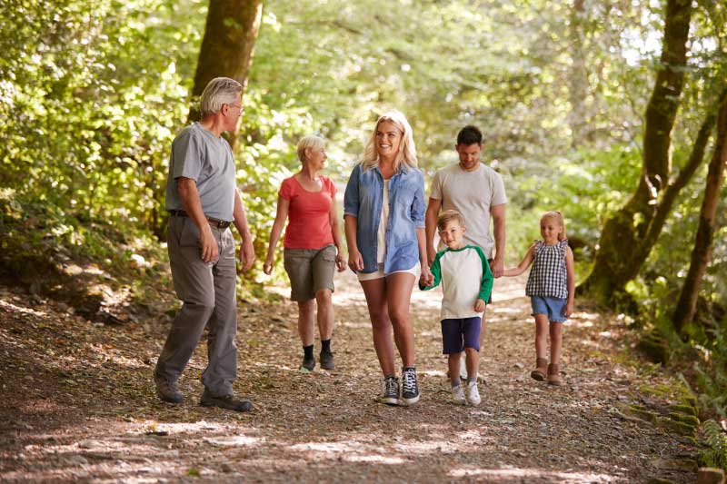 family of seven walking along an outdoor trail surrounded of trees