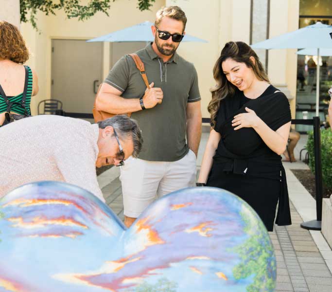 man and woman admiring a painted heart sculpture