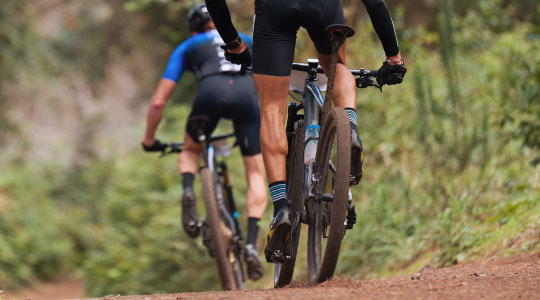 Two men cycling on a dirt path