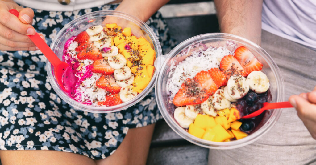 couple sitting together holding a couple of acai bowls