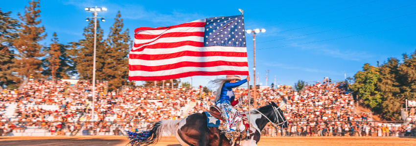 woman riding a horse while holding the American flag