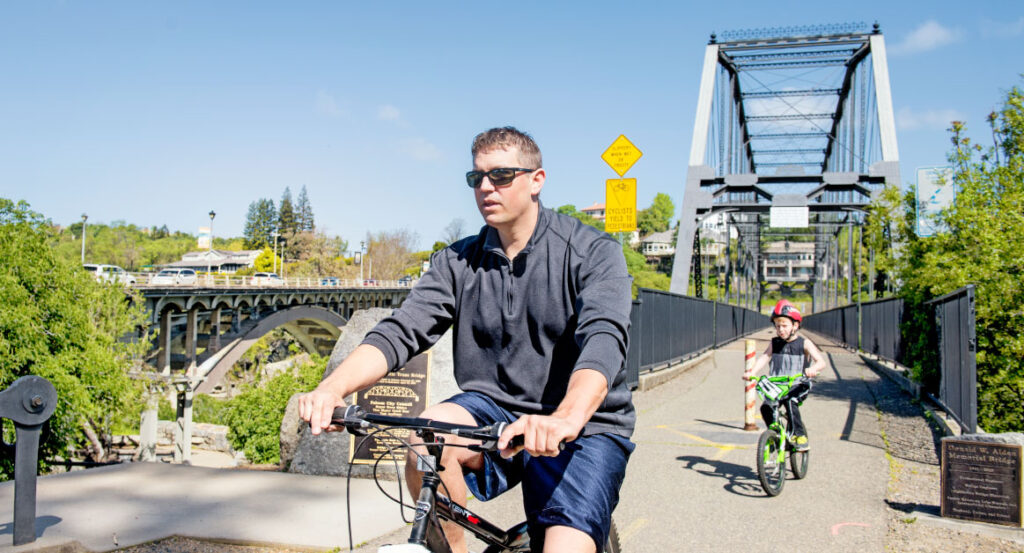 Father and son bike riding on truss bridge