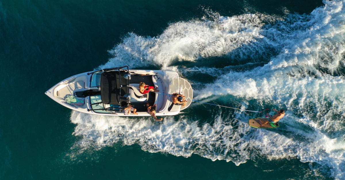 group of friends on a boat whole one is wake boarding