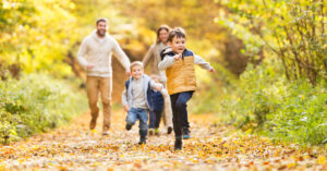family of four running through an autumn forrest