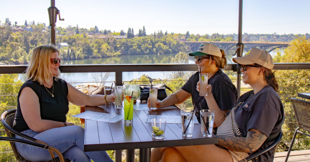 Three ladies enjoying cocktails at crawdads with the sunset in the background
