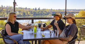 Three ladies enjoying cocktails at crawdads with the sunset in the background