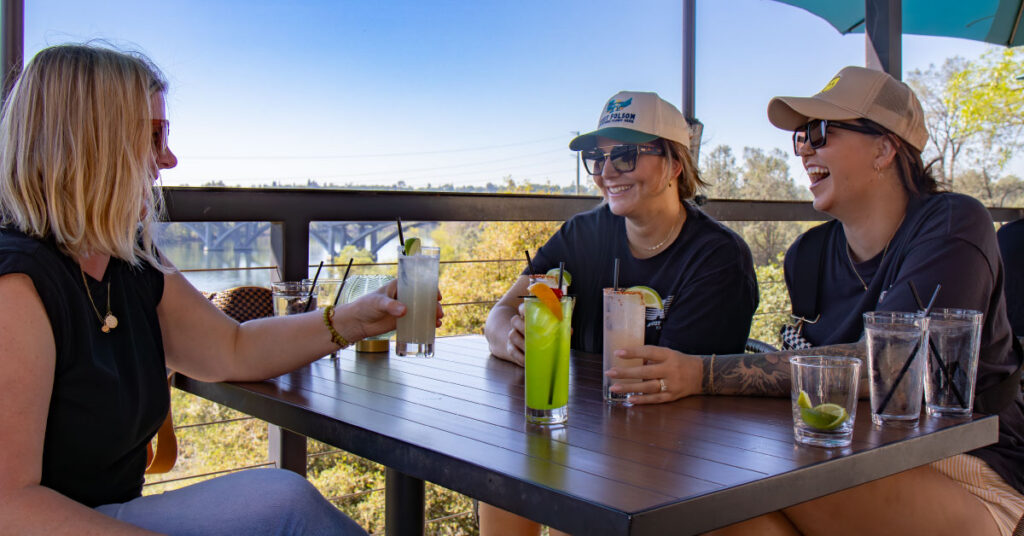 Three ladies enjoying cocktails at crawdads with the sunset in the background