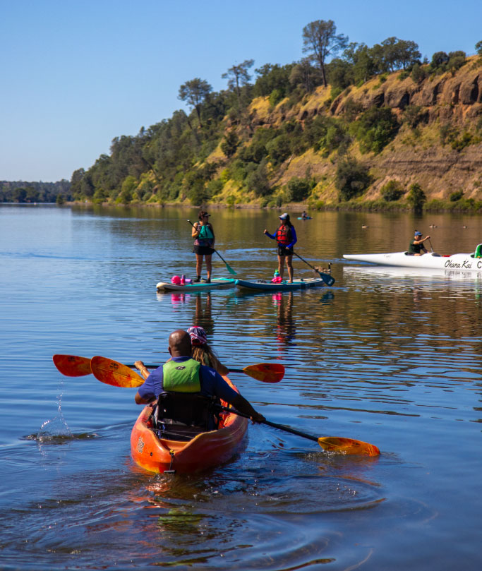 group of people kayaking and paddleboarding in lake natoma
