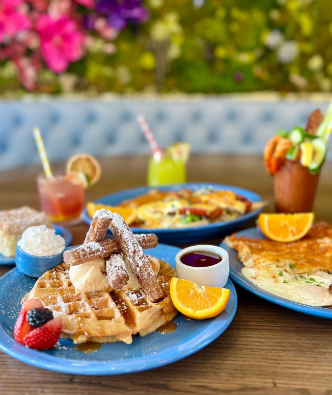table with bloody marys, waffles and various other brunch items